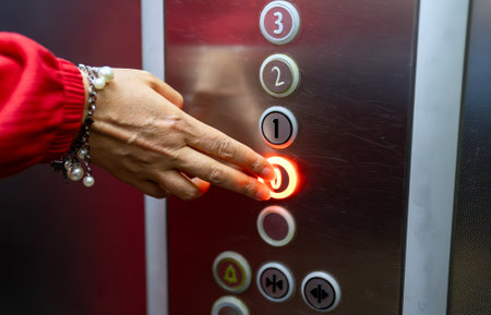 Woman in red dress pressing button inside elevator.の写真素材