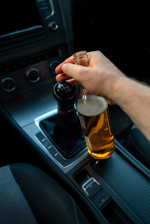 Man with a bottle of beer in the car. Drunk driving concept.