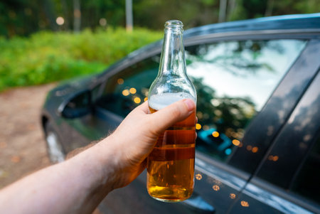 Man with a bottle of beer gets into a car. Drunk driving concept.の写真素材