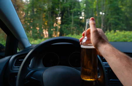 Man with a bottle of beer in the car. Drunk driving concept.