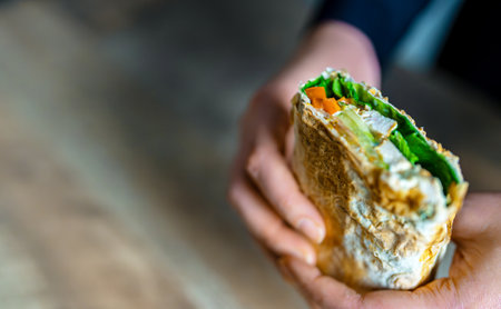 Woman holding shawarma with chicken and vegetables.の写真素材