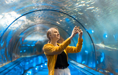 A woman in an underwater tunnel with sea creatures.の写真素材