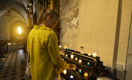 A woman lights a candle in a church.