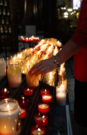 Woman putting candle near altar in church.の写真素材