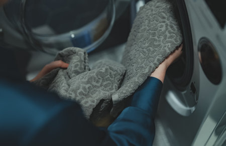 Woman loading laundry into a washing machine.の写真素材