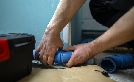 Man assembling plumbing pipes in the bathroom.