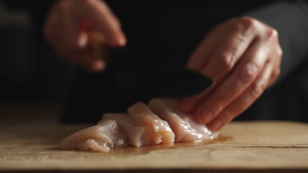 The cook cuts the chicken with a knife.の写真素材