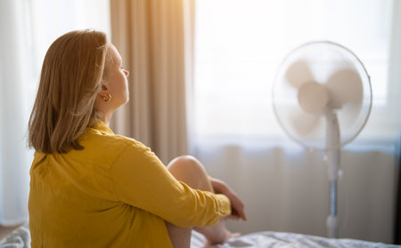 Woman suffering from extreme summer heat indoors.の写真素材