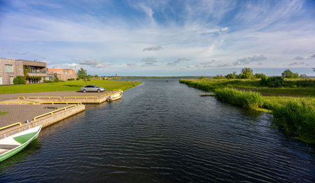 Calm river with moored boats, surrounded by greenery.の写真素材