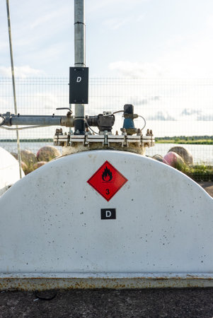 Industrial fuel storage tank with warning labels and piping system.の写真素材