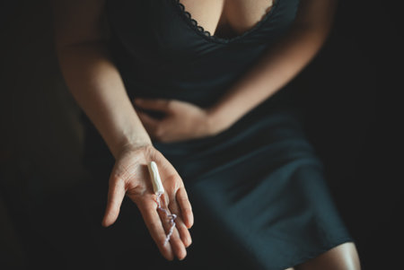 Woman holding tampon while sitting on toilet.の写真素材