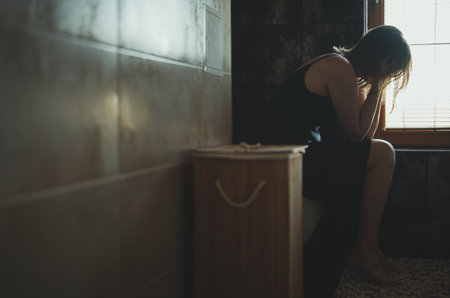 Upset woman covering face while sitting on toilet.の写真素材