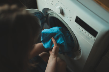 Woman loading laundry into a washing machine.の写真素材