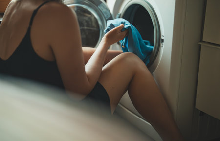 Woman loading laundry into a washing machine.の写真素材