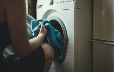 Woman loading laundry into a washing machine.の写真素材