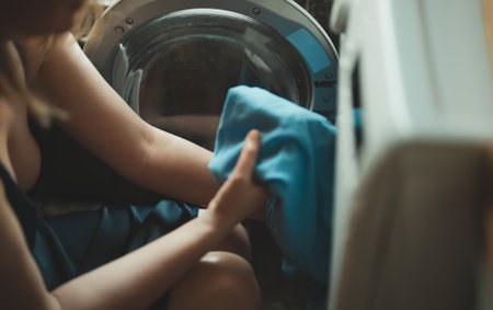 Woman loading laundry into a washing machine.の写真素材