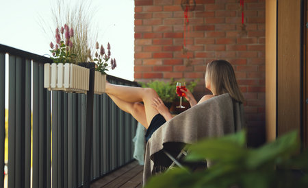 Woman enjoying her rose wine on balcony.の写真素材