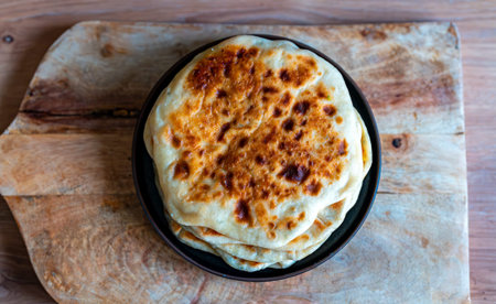 Freshly baked flatbreads served on wooden board.