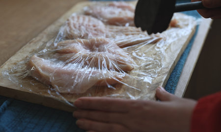 Tenderizing raw chicken fillet meat with mallet.の写真素材