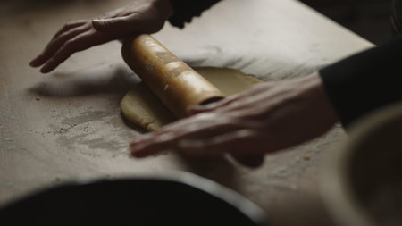 Female rolling out pastry dough with rolling pin.