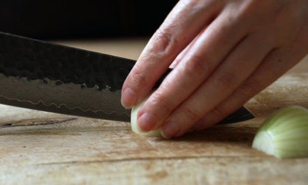 Female Chef Slicing Onion on Wooden Cutting Board.の写真素材