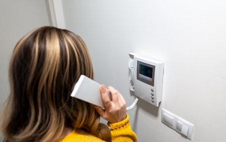 A woman is talking on the home intercom.の写真素材