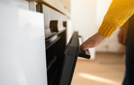 Woman opens the oven to start cooking.の写真素材