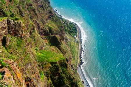 Vertical aerial view of a massive sea cliff and turquoise ocean.の写真素材