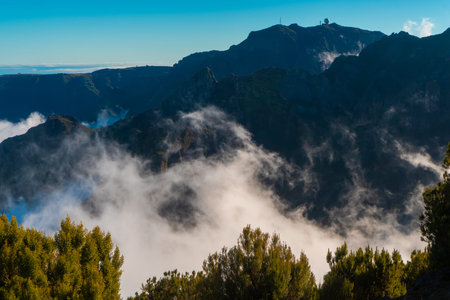 Dark mountain peaks with radar dome above the clouds.