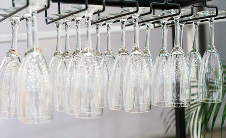 Rows of clean wine glasses hanging upside.