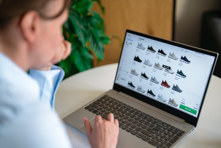 Woman choosing sneakers on e-commerce website using laptop.