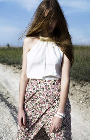 A girl stands in a field in the long hair on the faceの写真素材