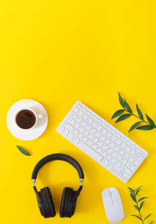 Yellow desktop with wireless headphones, laptop, mouse, cup of cofffe and plats top view. Music conceptの写真素材