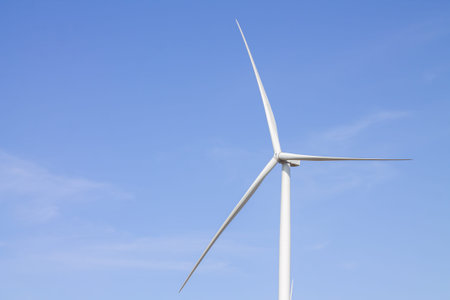 Close-up of wind turbine producing alternative energy on blue sky background