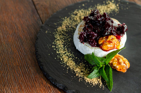 Fresh baked grilled camembert with cranberry sauce, herbs and caramelized walnuts close-upの写真素材