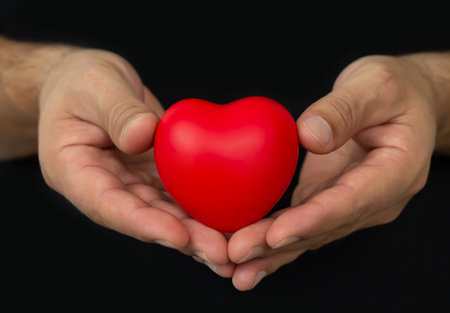 Man holging red heart on dark background. People, relationship, health and love conceptの写真素材
