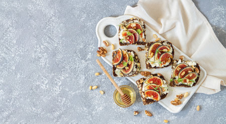 Toast with fresh figs, ricotta, nuts and honey on stone table, flat lay and copy spaceの写真素材