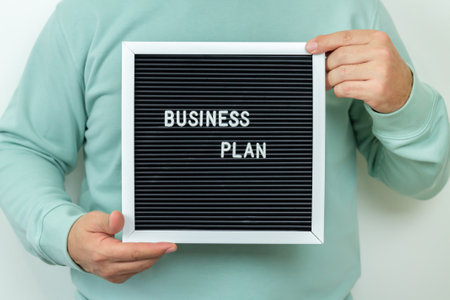 Businessman holding signboard with text "Business Plan". Entrepreneurship conceptの写真素材