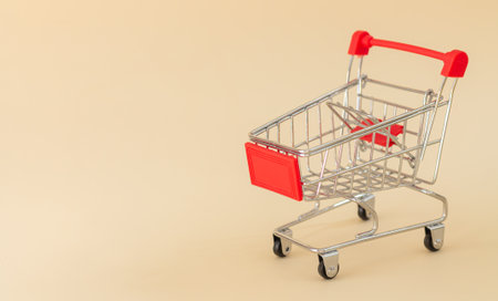 Empty red shopping cart or trolley on beige background with copy spaceの写真素材