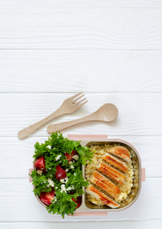 Lunch box full of delicious healthy food: fresh salad, coucous and grilled chicken top view on white wooden table with copy spaceの写真素材