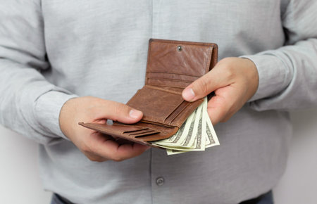 Man holding open leather wallet full of dollars