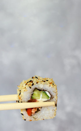 Eating sushi with chopsticks close-up. Japanese food sushi roll in restaurant. California roll with...