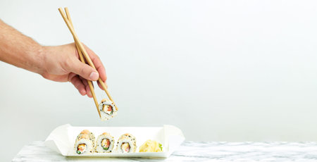 Man eating take away set of Japanese sushi. Delivery food concept