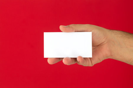 Businessman hand holding blank business card on red backgroundの写真素材