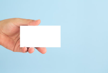Businessman hand holding blank business card on light blue background. Mock-up for your designの写真素材