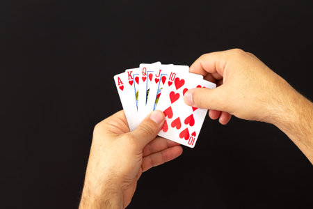 Male hands holding combination of royal flush poker cards on dark background. Casino, luck and...