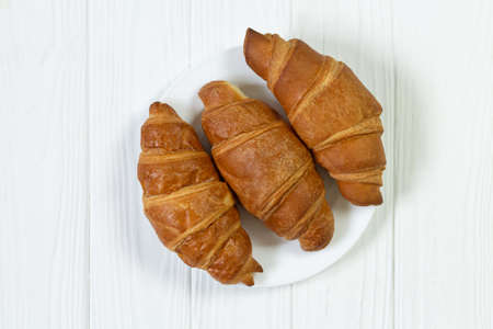 Plate of freshly baked croissants on white wooden table top viewの写真素材