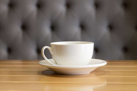 Clean white cup and saucer on wooden table in living room interiorの写真素材