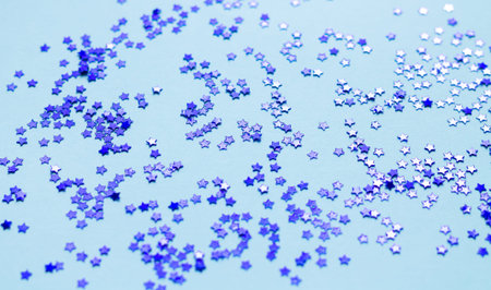 Blue shiny stars glitter or confetti on gray background top view