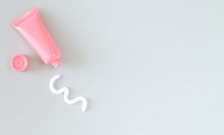 Plastic tube with squeezed out white cream stroke top view